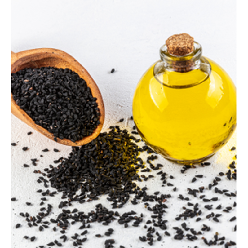 A bottle of Black Seed Oil beside black cumin seeds and delicate white Nigella flowers